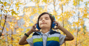 Junge mit Kopfhörer steht im Wald