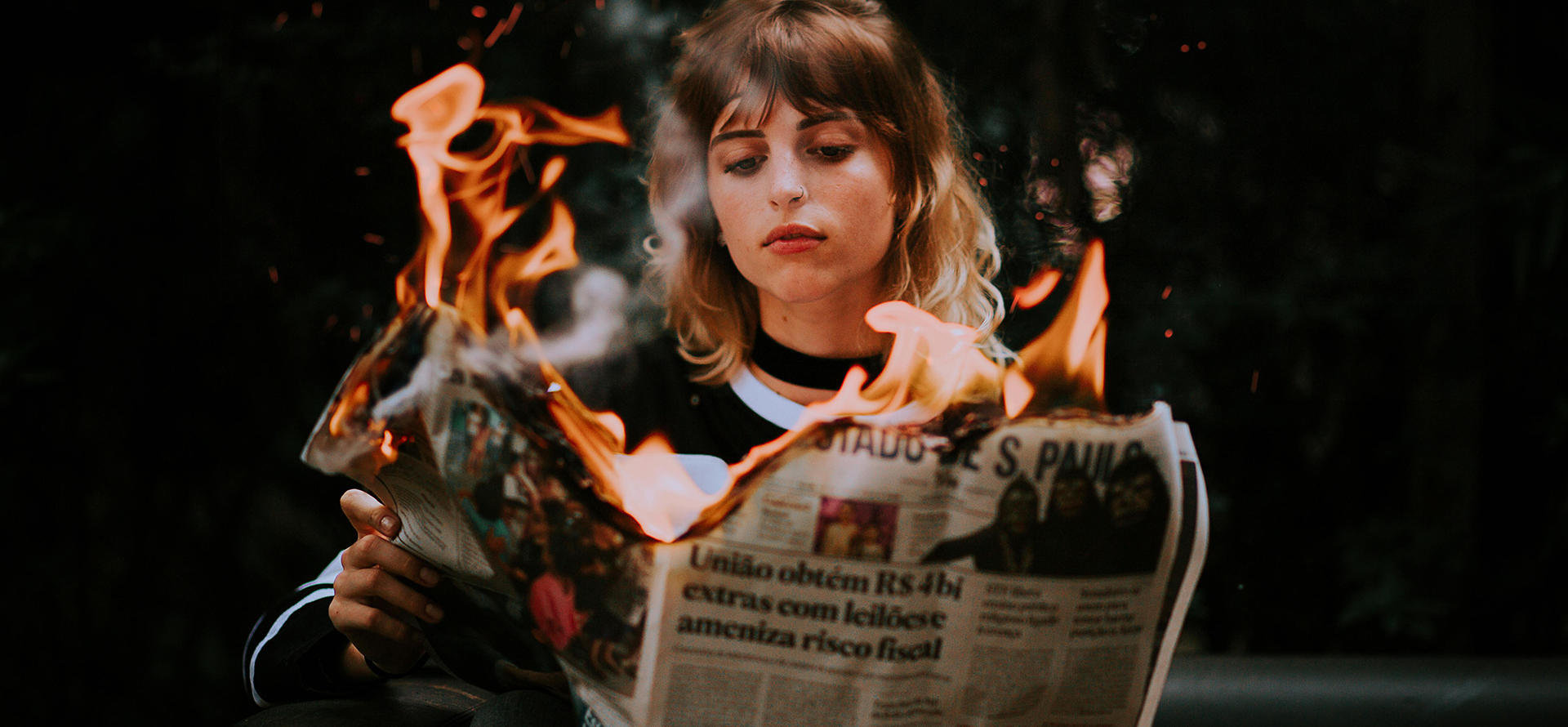 junge Frau liest in brennender Zeitung