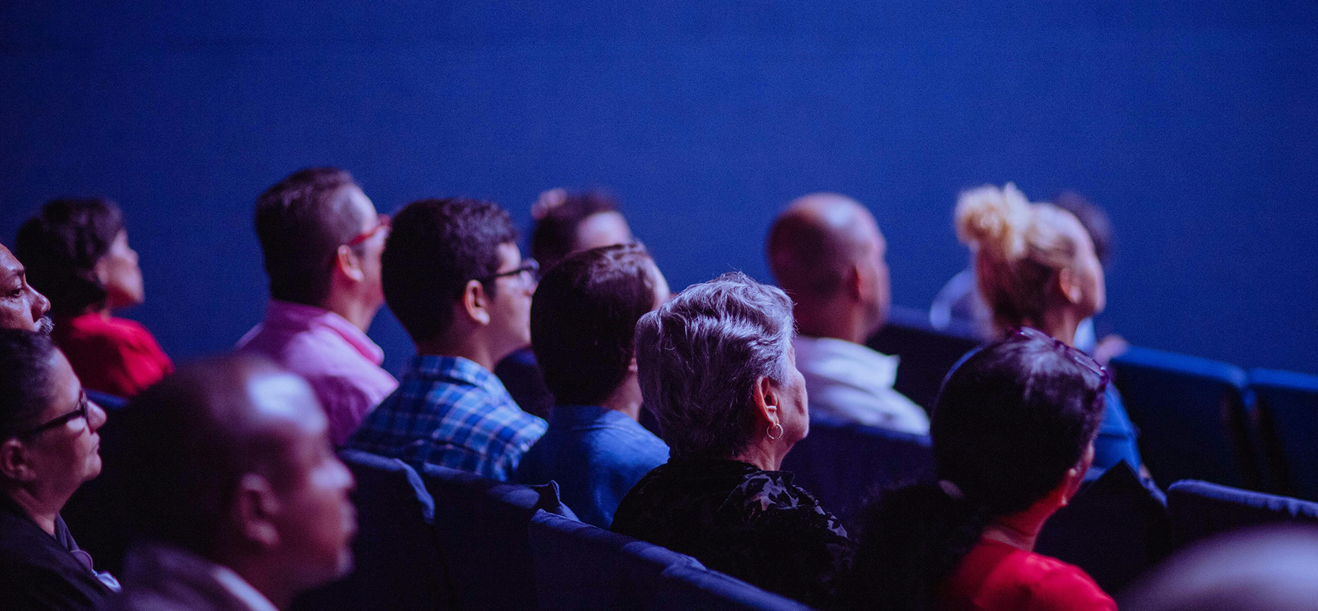 Symbolbild: mehrer Menschen sitzen im Kino und schauen auf die Leinwand